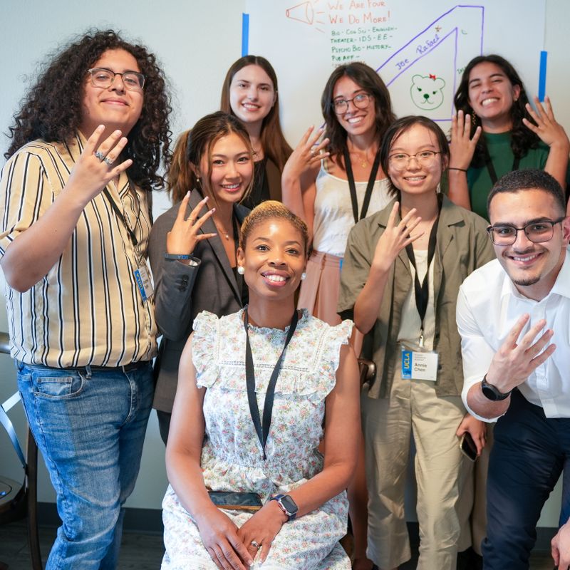 A group of UCLA faculty celebrating an accomplishment in front of a whiteboard