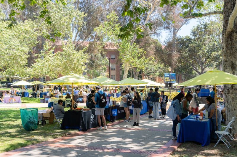 Students gather beneath yellow umbrellas and trees on UCLA’s campus during the Day of Hope mental health event, visiting resource tables and community booths promoting wellness, connection and student support.