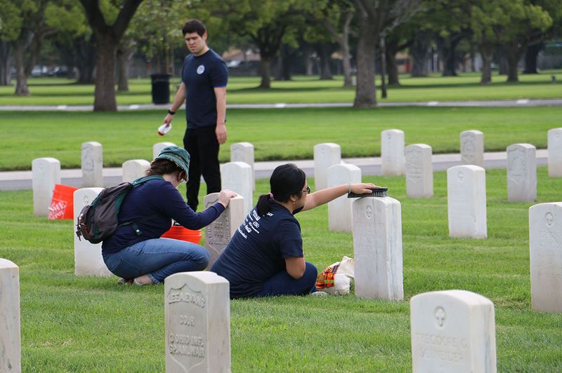 Volunteers clean grave stones at Veterans Memorial cemetery